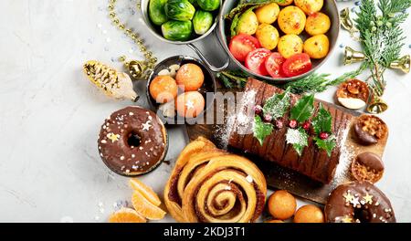 Köstlicher weihnachtlicher Esstisch mit gebratenem Fleisch, Kartoffeln, Vorspeisen und Desserts. Urlaubskonzept. Draufsicht auf grauem Hintergrund. Urlaub CO Stockfoto