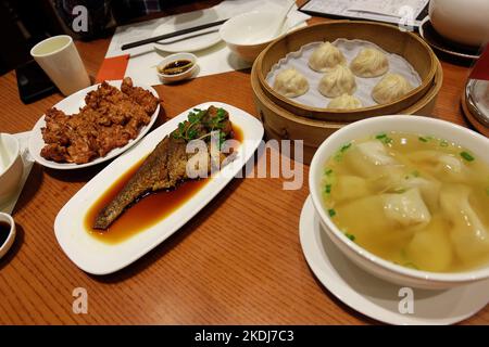 Chinesisches Dim Sum – frittiertes Schweinefleisch und Fisch, serviert mit Wonton-Nudelsuppe und Xiao Long Bao (mit Brühe gefüllte, gedünstete Schweineknödel aus Shanghaier) Stockfoto