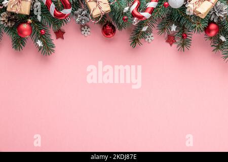 Weihnachtshintergrund mit Tannenbaum, Weihnachtsdekorationen, Geschenkboxen auf rosa Hintergrund. Flach liegend. Draufsicht mit Kopierbereich. Festlicher Hintergrund Stockfoto