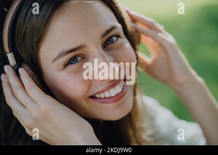 Porträt einer jungen Frau, die über Kopfhörer Musik hört. Stockfoto