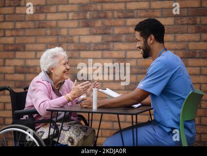 Pflegekraft erklärt der älteren Frau, wie sie Pillen nimmt. Stockfoto