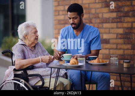 Pfleger beim Frühstück mit seinem Kunden im Café. Stockfoto