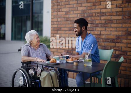 Pfleger beim Frühstück mit seinem Kunden im Café. Stockfoto