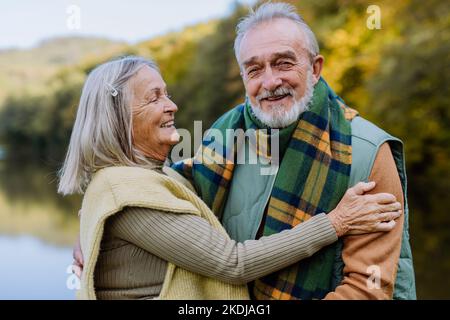 Das verliebte Senioren-Paar umarmt sich in der herbstlichen Natur. Stockfoto