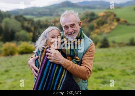 Das verliebte Senioren-Paar umarmt sich in der herbstlichen Natur. Stockfoto