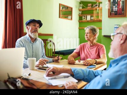 Ich bin offen für Ihre Vorschläge. Drei Senioren mit einem Treffen um einen Tisch zu Hause. Stockfoto