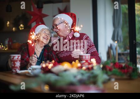 Glückliches Seniorenpaar feiert Heiligabend mit Wunderkerzen. Stockfoto