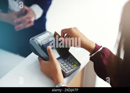 Ein Swipe und du bist alle bezahlt. Eine unkenntliche Person wischen eine Kreditkarte für die Zahlung. Stockfoto