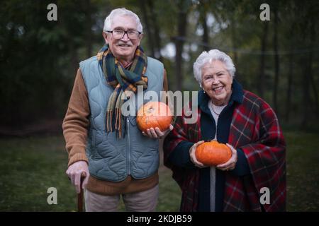 Seniorenpaar mit Kürbissen im Herbstwald. Stockfoto