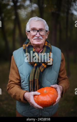 Älterer Mann mit Kürbissen im Herbstwald. Stockfoto