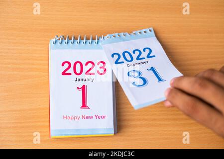 Nahaufnahme der Hände, die den Kalender auf Neujahr 2023 ändern, indem 2022 entfernt wird - Konzept der Neuanfänge Stockfoto