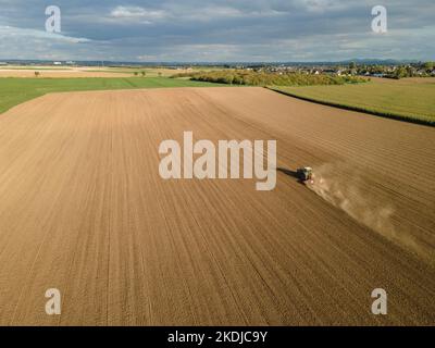 Ein Traktor pflügt im Sonnenuntergang ein Feld Stockfoto
