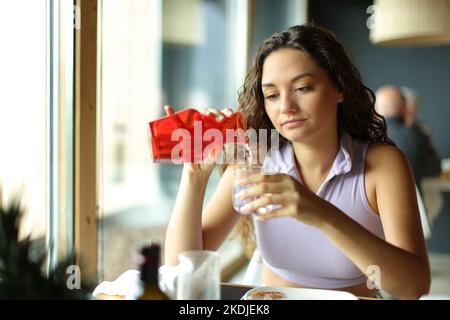 Frau, die ein Glas Wasser aus der Flasche in einem Restaurant füllte Stockfoto