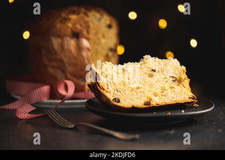 Panettone-Weihnachtskuchen. Italienisches süßes Brot auf dem Teller auf dem dunklen Tisch. Stockfoto