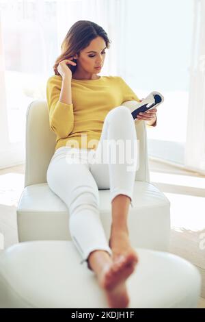 Eine junge Frau, die ein Buch liest, während sie sich zu Hause entspannt. Stockfoto