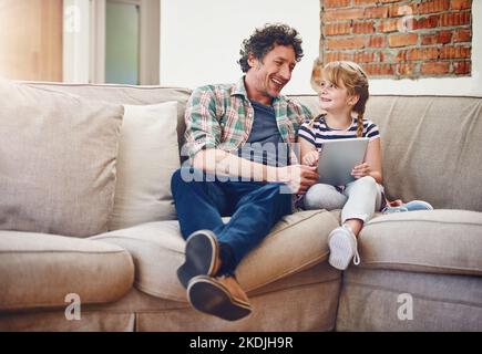 Sollen wir uns unseren Lieblingsfilm ansehen? Ein Vater und seine kleine Tochter benutzen zu Hause ein digitales Tablet. Stockfoto