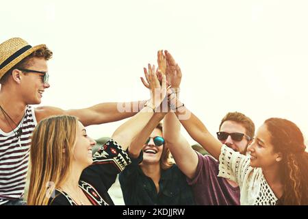 Yay US. Eine glückliche Gruppe von Freunden hoch fiving am Strand. Stockfoto