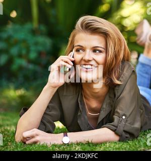 Ich bin einfach nur abschreckend... eine attraktive junge Frau, die draußen auf ihrem Handy spricht. Stockfoto