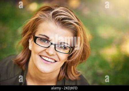 Draußen zu sein bringt mich immer zum Lächeln. Porträt einer attraktiven jungen Frau, die einen Tag im Park genießt. Stockfoto