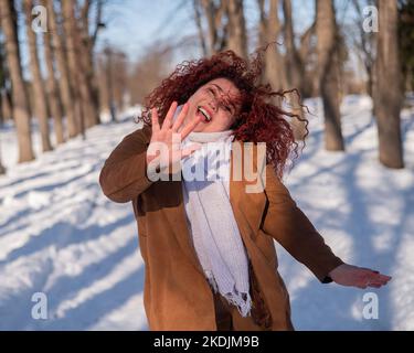 Die fette kaukasische Frau tanzt im Winter auf einem Spaziergang im Park. Stockfoto