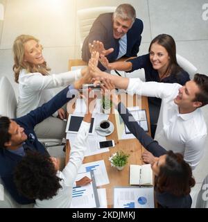 Lassen Sie uns dies zu unserem bisher besten Gewinn machen. Aufnahme einer Gruppe von Geschäftsleuten, die sich in einem Büro zusammengeschlossen haben. Stockfoto