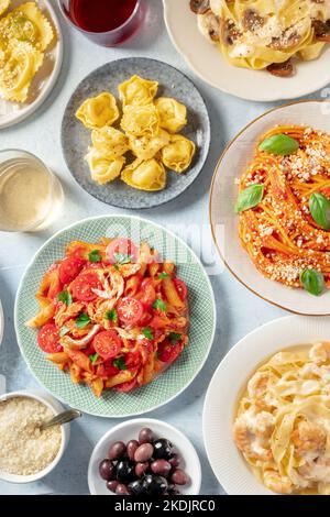 Italienische Pasta, verschiedene Gerichte, über Kopf flach lay shot. Spaghetti, Penne mit Huhn, Garnelen Pappardelle, mit geriebenem Parmesan-Käse, фтв-Wein Stockfoto