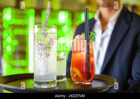Ein Nachtclub-Kellner trägt das Tablett mit Cocktails Stockfoto
