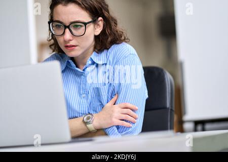 Junge Geschäftsfrau, die ein Notebook nutzt, schaut sich das Online-Webinar am Arbeitsplatz an. Stockfoto