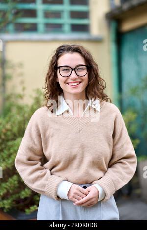 Junge lächelnde professionelle Geschäftsfrau im Freien stehend, vertikales Porträt. Stockfoto