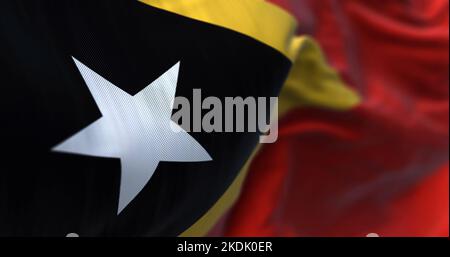Nahaufnahme des Winkens der Nationalflagge von Osttimor. Die Demokratische Republik Osttimor ist ein Land in Südostasien. Texturierter Hintergrund aus Stoff. Se Stockfoto