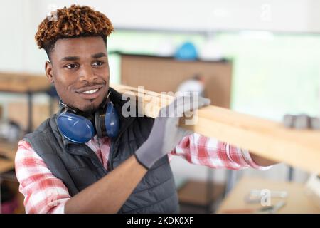 Reifer männlicher Arbeiter mit gefesselten Holzbohlen auf der Baustelle Stockfoto