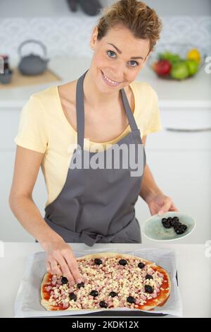 Frau macht Pizza zu Hause Stockfoto