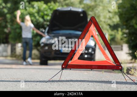 Sicherheitsdreieck am Straßenrand, nachdem das Frauenauto ausgefallen ist Stockfoto