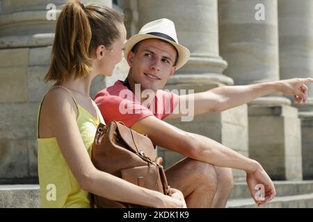 Das junge Paar saß auf den Stufen des großen Gebäudes Stockfoto