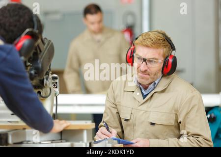 Zwei Männer bei der Arbeit Operationsmaschine zum Schneiden von Holzplatten Stockfoto