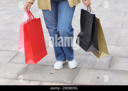 Cropped Portrait von unkenntlich Frau mit bunten Einkaufstaschen auf städtischen Einkaufszentrum Hintergrund. Käufe, Black friday, Rabatte, Verkauf konz Stockfoto