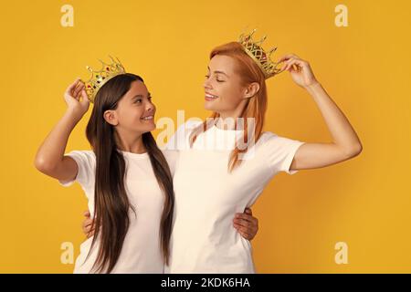 Königinnen in Tiara. Lustige Familie auf gelbem Hintergrund. Mutter und Tochter Mädchen mit Krone. Zwei Prinzessin. Stockfoto