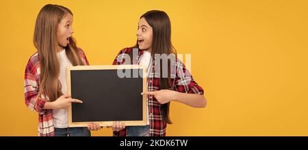 Schule Mädchen Freunde. Überraschte Kinder in lässig kariert zeigt Schule Tafel für Kopie Raum, Schulverkauf. Banner der Schülerin Stockfoto