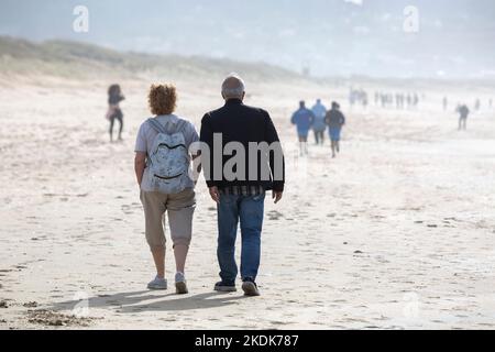 Ein Paar mittleren Alters geht Hand in Hand am Strand Von A Lanzada, O Grove Stockfoto