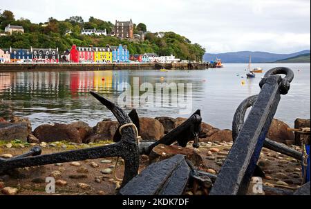 Ein Blick auf hell gestrichene Gebäude mit Reflexionen und Vordergrundankern am Burgh von Tobermory, Isle of Mull, Argyll und Bute, Schottland. Stockfoto