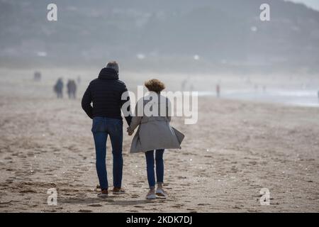 Ein Paar mittleren Alters geht Hand in Hand am Strand Von A Lanzada, O Grove Stockfoto