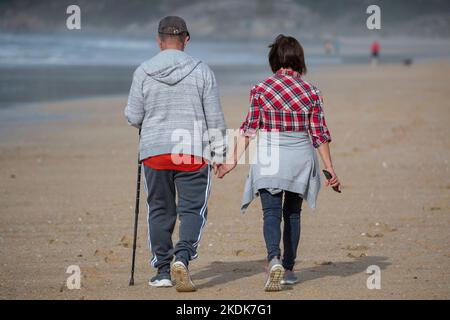 Ein Paar mittleren Alters geht Hand in Hand am Strand Von A Lanzada, O Grove Stockfoto