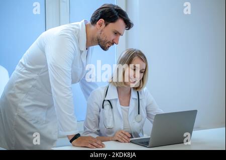 Zwei Menschen in Laborkittel diskutieren etwas und schauen interessiert Stockfoto