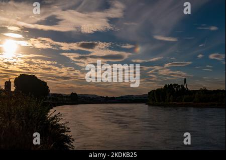 Schillernde Wolken bei Sonnenuntergang über dem Rhein in Neuwied Deutschland Stockfoto