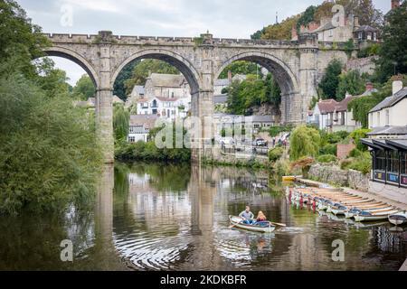 KNARESBOROUGH, Großbritannien - 20. September 2022. Touristen mieten ein Ruderboot auf dem Fluss Nidd unterhalb des Knaresborough Railway Viaduct, Knaresborough, North Yorksh Stockfoto