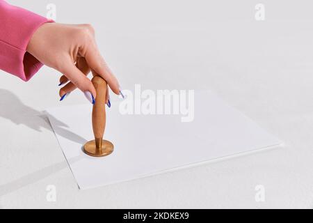 Weibliche Hand Putting Stempel auf Papier Dokument symbolisieren Erlaubnis auf weißem Hintergrund Stockfoto