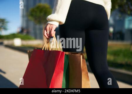 Nahaufnahme einer Frau, die mit Einkaufstaschen in der Stadt vom Einkaufszentrum aus läuft. Low-Winkel-Ansicht von Mädchen gehen mit Käufen aus schwarzen freitag Verkauf. Weiblich Stockfoto