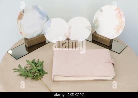Leeres rosafarbenes Buch, Tagebuch, Hochzeitsgastbuch, Notebook-Modell. Objekt für Design und Branding. Schöne grüne Pflanze, textile Textur, Draufsicht. Stockfoto