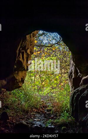 Blick von einem höhlenartigen Eingang auf eine alte verlassene Bleimine in Middleton Dale in der Nähe von Stoney Middleton, Derbyshire. Stockfoto