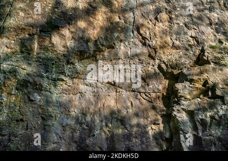 Hohe Kalksteinfelsen, teilweise bebaut, mit Höhleneingängen und künstlichen Eingängen für Bleiminen, in Middleton Dale, Stoney Middleton, Peak District. Stockfoto